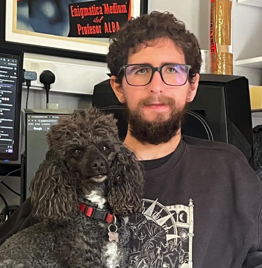 Tim with his dog Red, who has black curly fur, sitting on his lap